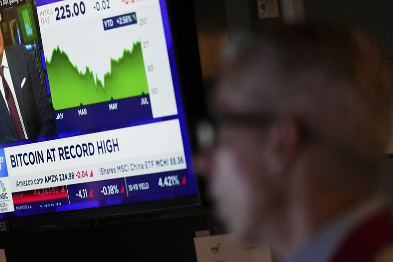 Una televisión muestra información financiera en el piso de remates de la Bolsa de Valores de Nueva York, el lunes 14 de julio de 2025. (AP Foto/Seth Wenig)