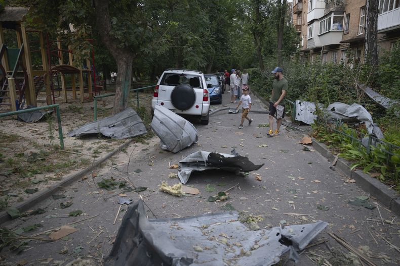 Residentes pasan junto a escombros caídos de una vivienda dañada en un ataque ruso con proyectiles sobre Kiev, Ucrania, el 30 de agosto de 2023. (AP Foto/Efrem Lukatsky)