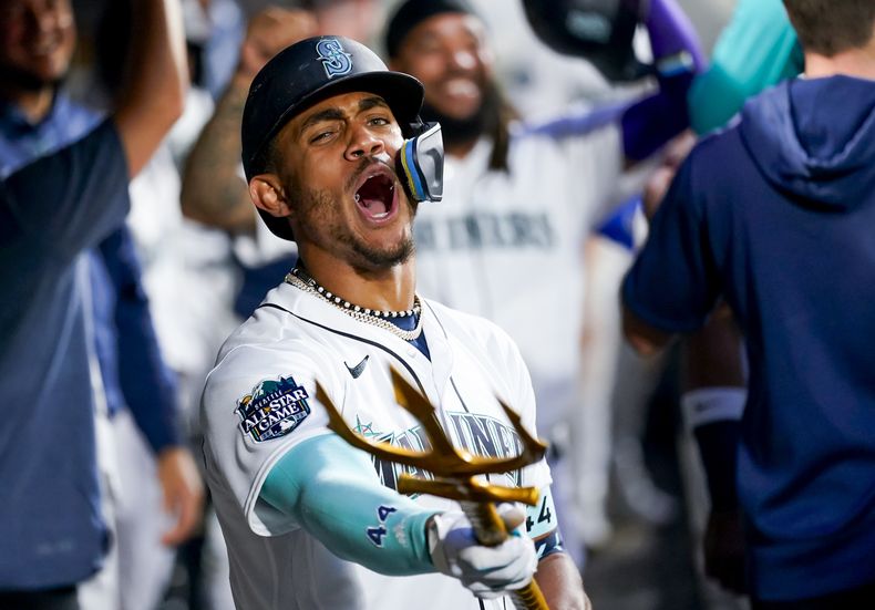 El dominicano de los Marineros de Seattle Julio Rodriguez apunta con el tridente en el dugout celebrando su jonrón de dos carreras en la cuarta entrada del juego ante los Atléticos de Oakland el lunes 28 de agosto del 2023. (AP Foto/Lindsey Wasson)