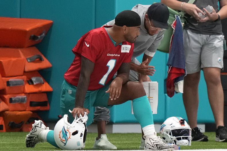 El quarterback de los Dolphins de Miami Tua Tagovailoa habla con el entrenador Mike McDaniel durante un entrenamiento el miércoles 24 de julio del 2024. (AP Foto/Lynne Sladky)
