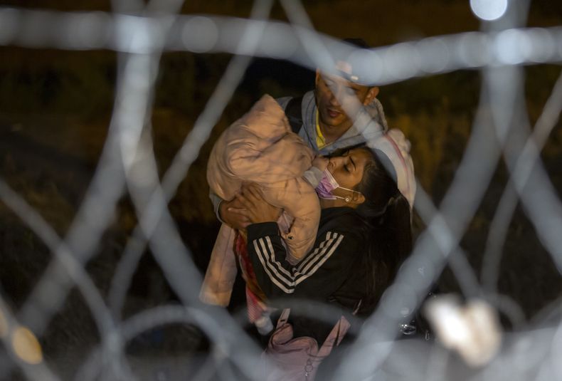 Una pareja de migrantes cargan a su bebé mientras se aproximan a una puerta en el muro fronterizo en las primeras horas del jueves 11 de mayo de 2023, después de cruzar desde Ciudad Juárez, México, hacia El Paso, Texas. Gran cantidad de migrantes se apresuraban a cruzar la frontera entre México y Estados Unidos horas antes de que concluyan las restricciones al asilo relacionadas con la pandemia de COVID-19, ante el temor de que las nuevas políticas les dificulten más entrar a territorio estadounidense. (AP Foto/Andrés Leighton)
