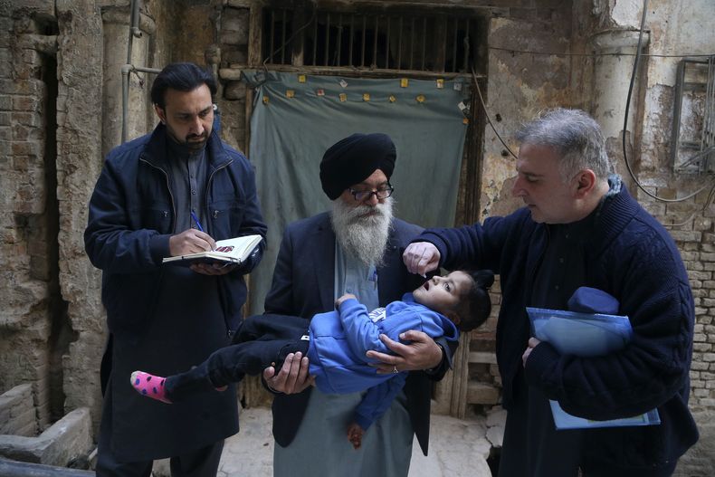 Un trabajador de salud (der) le da la vacuna contra el polio a un niño en Peshawar, Pakistán, el 3 de febrero del 2025. (AP foto/Muhammad Sajjad)