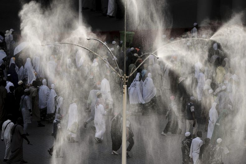 Unos dispositivos rocían agua sobre los peregrinos musulmanes que depositan piedras sobre unos pilares, en una lapidación simbólica del diablo, uno de los ritos de la peregrinación anual del haj, en Mina, cerca de la ciudad santa de La Meca, Arabia Saudí, el 7 de junio de 2025. (AP Foto/Amr Nabil)