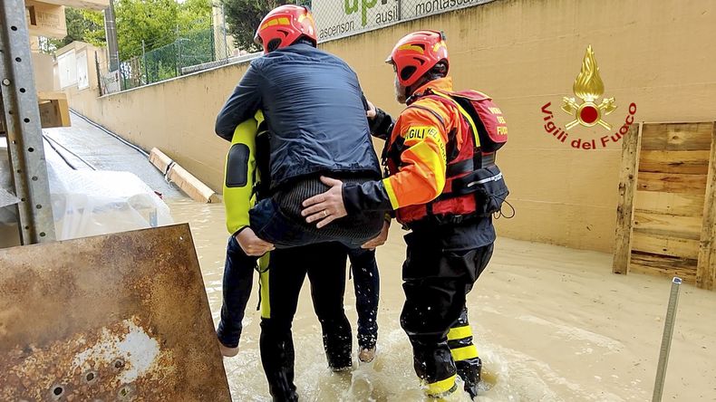 Esta foto facilitada por los bomberos italianos muestra a socorristas que retiran a una persona de una casa inundada en Riccione, en la región norteña italiana de Emilia-Romaña, el martes 16 de mayo de 2023. (Vigili del Fuoco vía AP)