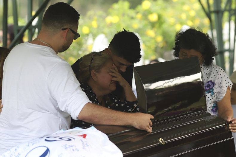 La familia de Alberto Antonio Palacios, uno de los hinchas de fútbol que murieron en la estampida en el estadio Cuscatlán, guarda luto durante su sepelio en el cementerio Jardines del Recuerdo en San Salvador, El Salvador, el lunes 22 de mayo de 2023. (AP Foto/Salvador Meléndez)
