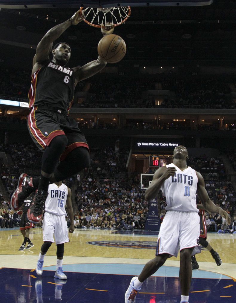 LeBron James (6), del Heat de Miami, cuelga del aro despu&eacute;s de clavar el bal&oacute;n frente a Bismack Biyombo (0), de los Bobcats de Charlotte, en la primera mitad del juego del s&aacute;bado 16 de noviembre de 2013, en Charlotte, Carolina del Nor