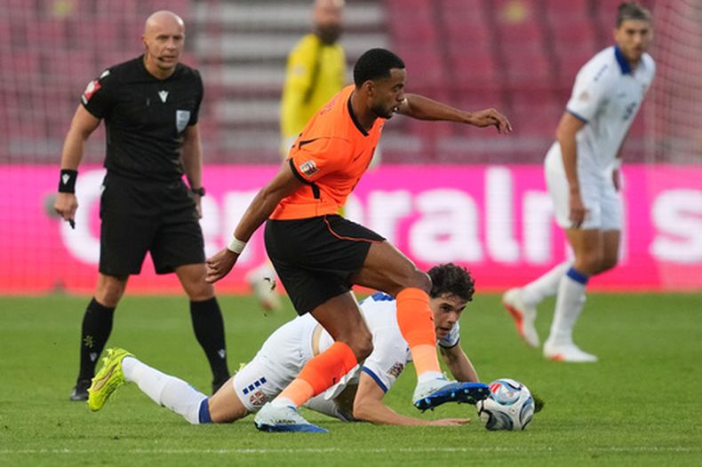 El serbio Petar Sukacev (en el piso) observa al neerlandés Cody Gakpo controlar el balón durante el partido de la Liga de Naciones, el domingo 27 de septiembre de 2026, en Belgrado. (AP Foto/Darko Vojinovic)