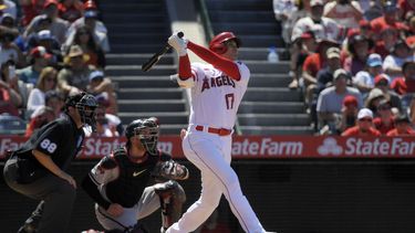 Shohei Ohtani, derecha, de los Angelinos de Los Ángeles, batea un cuadrangular solitario mientras que Gabriel Moreno, dentro, receptor de los Diamondbacks de Arizona, y el umpire del plato, Doug Eddings, observan durante la octava entrada del juego de béisbol, el domingo 2 de julio de 2023, en Anaheim, California. (AP Foto/Mark J. Terrill)