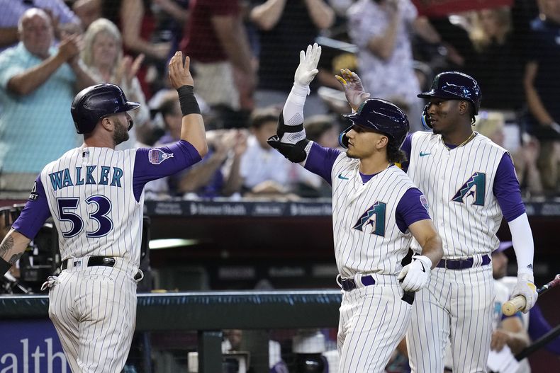 Christian Walker celebra con sus compañeros de los Diamondbacks de Arizona Alek Thomas y Geraldo Perdomo en la octava entrada del encuentro ante los Padres de San Diego el domingo 13 de agosto del 2023. (AP Foto/Ross D. Franklin)