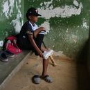 Yeferson Seijas se pone sus zapatos deportivos para un entrenamiento de béisbol en La Guaira, Venezuela, el sábado 11 de julio de 2026, después de que los sismos dejaran a su familia sin hogar, y de que algunos de los niños con los que creció jugando acabaran lesionados, huérfanos, muertos o desaparecidos. (AP Foto/Ariana Cubillos)