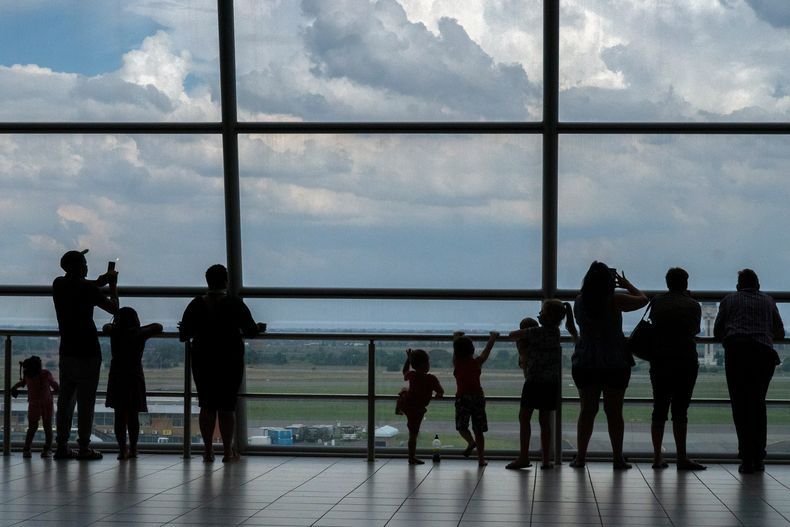 Personas observan aviones en la pista del Aeropuerto Internacional O.R. Tambo de Johannesburgo, Sudáfrica, el lunes 29 de noviembre de 2021. (Foto AP/Jerome Delay, Archivo)