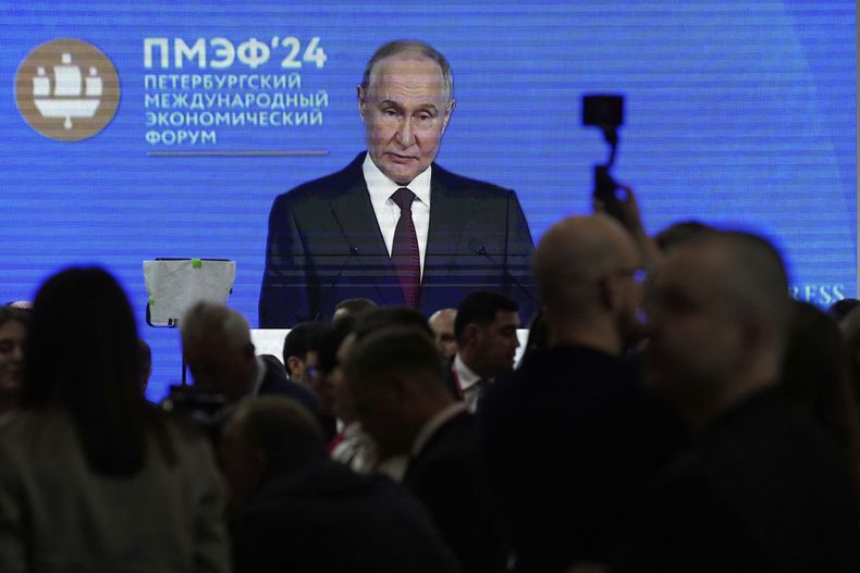 Personas caminan frente a una pantalla que muestra al presidente ruso Vladímir Putin en los márgenes del Foro Económico Internacional de San Petersburgo, en San Petersburgo, Rusia, el miércoles 18 de junio de 2025. (AP Foto/Dmitri Lovetsky)