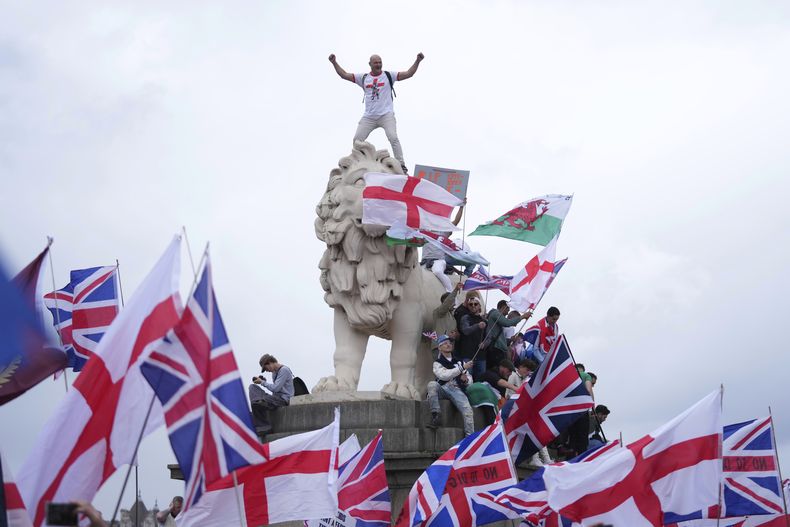 Un manifestante se ve sobre el león en la orilla sur del puente de Westminster, durante la marcha Unir el Reino convocada por Tommy Robinson en Londres, el sábado de 13 de septiembre de 2025. (AP Foto/Joanna Chan)