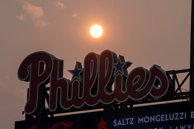 El Sol tiene un matiz anaranjado debido al humo proveniente de los incendios forestales de Canadá mientras se pone cerca de la pizarra de los Filis de Filadelfia durante la cuarta entrada de un partido de béisbol contra los Mets de Nueva York, el jueves 16 de julio de 2026, en Filadelfia. (Foto AP/Chris Szagola)
