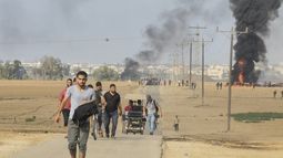 Palestinos se alejan del kibbutz de Kfar Azza, Israel, cerca de la valla fronteriza de la Franja de Gaza, el 7 de octubre de 2023. (AP Foto)