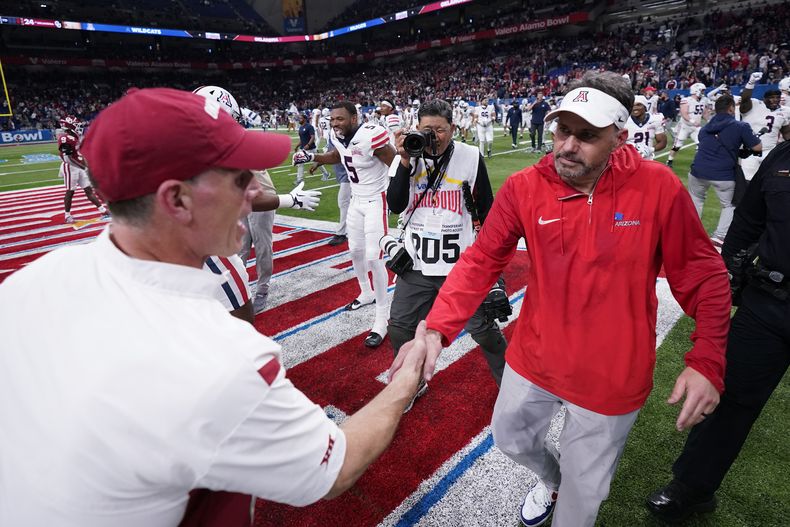 Brent Venables, izquierda, head coach de Oklahoma, y el head coach de Arizona Jedd Fisch, derecha, se saludan después del Alamo Bowl en San Antonio, el jueves 28 de diciembre de 2023. Fisch será el nuevo entrenador en jefe de Washington, dijo una persona a The Associated Press el domingo 14 de enero de 2023. (AP Foto/Eric Gay)