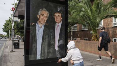 Una activista coloca un cartel del ahora presidente Donald Trump con Jeffrey Epstein, en una parada de autobús cerca de la embajada de Estados Unidos en Londres, el jueves 17 de julio de 2025. (AP Foto/Thomas Krych)