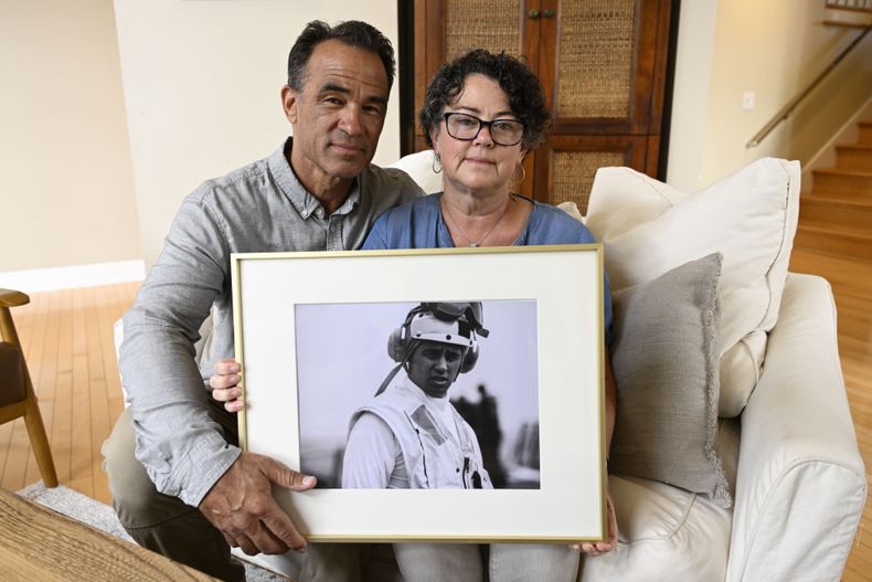 ARCHIVO - Derek y Suzi Alkonis posan con una foto de su hijo, el teniente de navío Ridge Alkonis, 1 de junio de 2022 en Dana Point, California, EEUU. El teniente de navío Ridge Alkonis, un oficial de la armada estadounidense encarcelado en Japón por un accidente de tráfico en que murieron dos ciudadanos japoneses, ha sido transferido a las autoridades estadounidenses, se informó el jueves 14 de diciembre de 2023. (AP Foto/Denis Poroy, File)