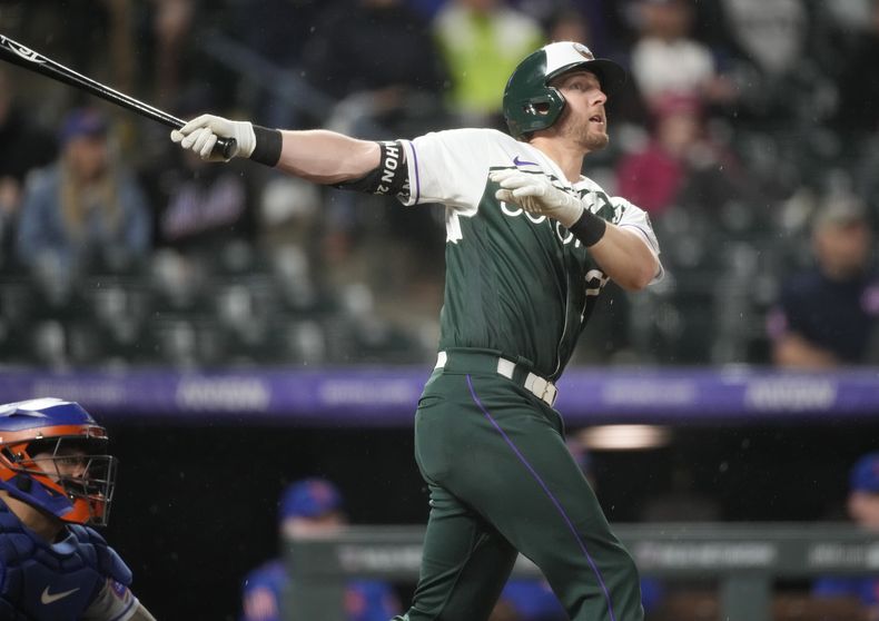 Ryan McMahon, de los Rockies de Colorado, observa la pelota al conectar un jonrón de dos carreras en el juego del sábado 27 de mayo de 2023 ante los Mets de Nueva York (AP Foto/David Zalubowski)