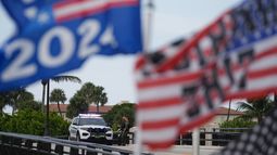 Policías resguardan un puente ubicado a un costado de la finca Mar-a-Lago del expresidente Donald Trump mientras un simpatizante ondea banderas para expresar su apoyo a Trump, un día después de un aparente intento de asesinato en su contra, el lunes 16 de septiembre de 2024, en Palm Beach, Florida. (AP Foto/Rebecca Blackwell)