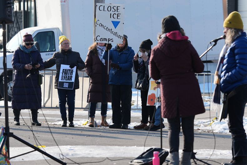 Manifestantes se reúnen mientras agentes vigilan el exterior de un centro de procesamiento del ICE en el suburbio de Broadview, Illinois, en Chicago, el viernes 12 de diciembre de 2025. (AP Foto/Nam Y. Huh)