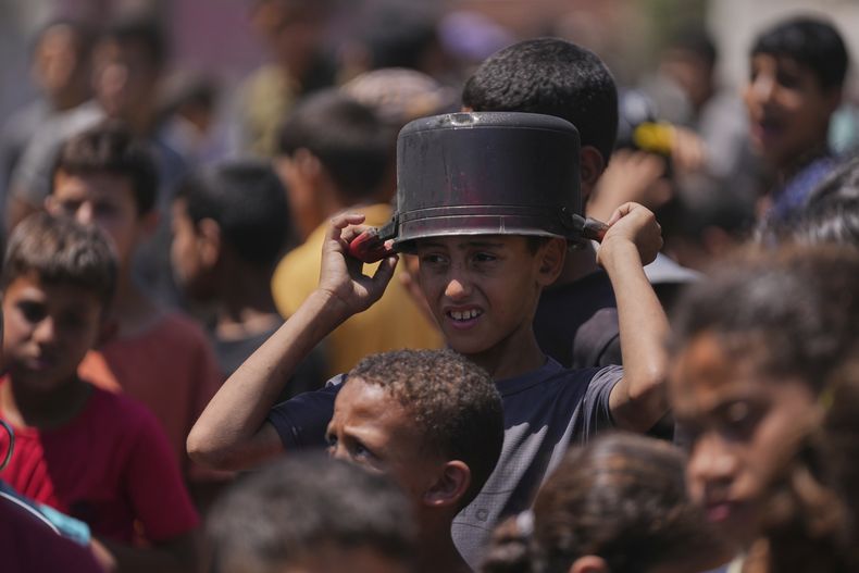 Un niño palestino espera para recibir comida donada en un centro de distribución de alimentos en Deir al-Balah, Franja de Gaza, el viernes 30 de mayo de 2025. (AP Foto/Abdel Kareem Hana)