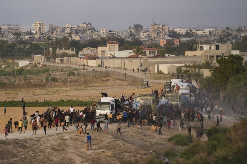 ARCHIVO - Palestinos se acercan a camiones con ayuda humanitaria que entraron al enclave a través de un nuevo puente construido por Estados Unidos, en el centro de la Franja de Gaza, el 18 de mayo de 2024. (AP Foto/Abdel Kareem Hana, Archivo)
