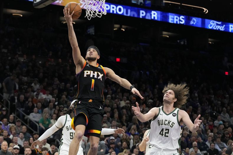 Devin Booker, de los Suns de Phoenix, avanza junto a Robin López (42), de los Bucks de Milwaukee, en el partido del martes 6 de febrero de 2024 (AP foto/Ross D. Franklin)