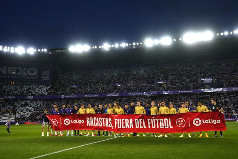 Los jugadores del Barcelona y el Valladolid exhiben una pancarta con la frase Racistas, fuera del fútbol previo al partido de la Liga española, el martes 23 de mayo de 2023, en Valladolid. (AP Foto/Manu Fernández)
