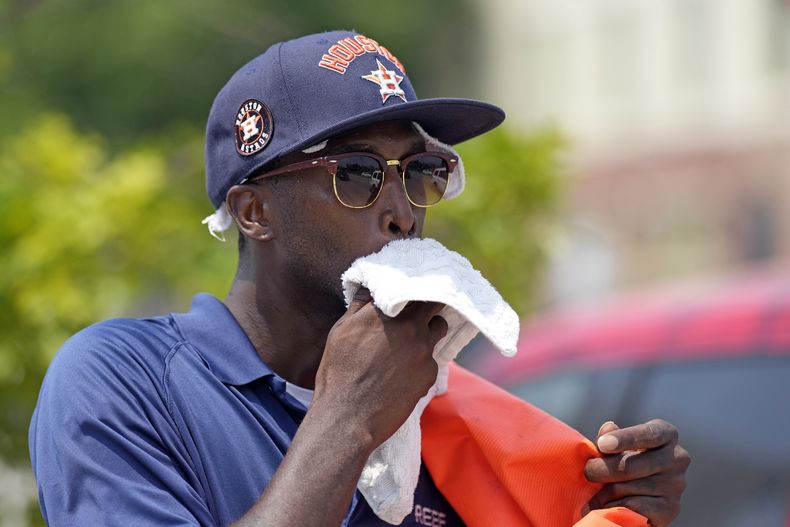Donnay Wright, quien trabaja en un estacionamiento, se limpia el sudor del rostro mientras trabaja afuera del Minute Maid Park antes de un partido de béisbol entre los Rojos de Cincinnati y los Astros de Houston el sábado 17 de junio de 2023, en Houston. (AP Foto/David J. Phillip)