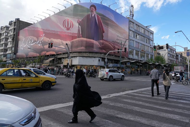 La gente pasa junto a una valla publicitaria que muestra un gráfico que representa al Líder Supremo de Irán, el ayatolá Mojtaba Jamenei, en el centro de Teherán, Irán, el lunes 6 de abril de 2026. (Foto AP/Vahid Salemi)