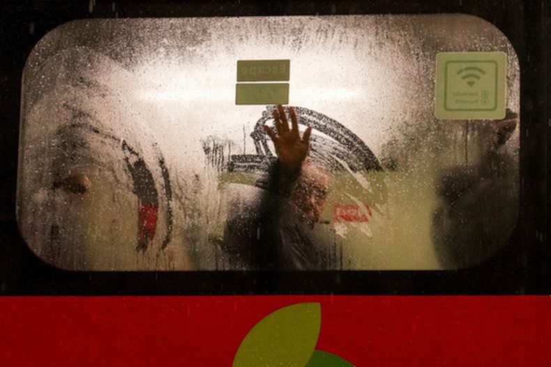 Un hombre limpia la condensación en la cara interior de la ventana de un autobús durante una tormenta, en Santiago, Chile, el 20 de julio de 2026. (AP Foto/Esteban Felix)