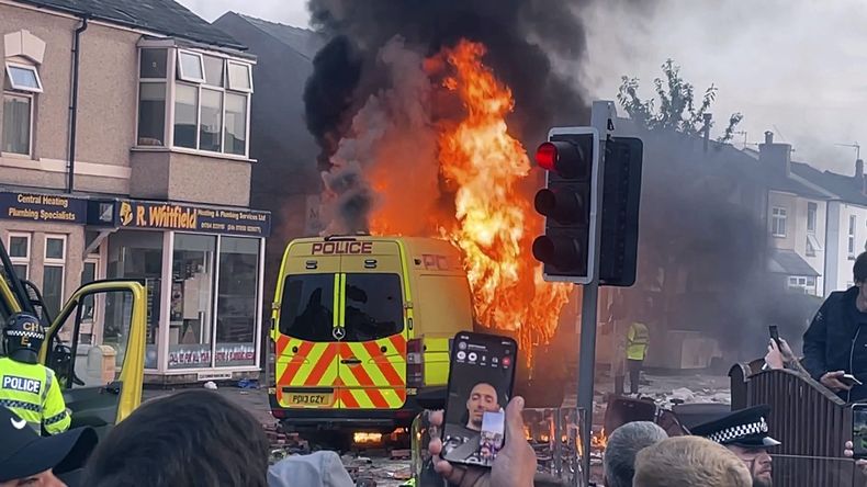 Una camioneta policial arde mientras una multitud choca con al policía el martes 30 de julio de 2024 en Southport, en el noroeste de Inglaterra, donde tres niñas murieron tras ser apuñaladas el día anterior. (Richard McCarthy/PA via AP)