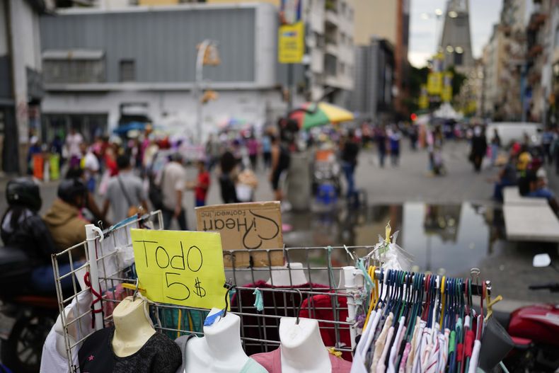 ARCHIVO - Un cartel dice Todo 5 dólares en perchero ante una tienda en Caracas, Venezuela, el 3 de octubre de 2023. (AP Foto/Matias Delacroix, Archivo)