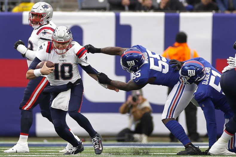 El linebacker de los Giants de Nueva York Jihad Ward (55) sujeta al quarterback de los Patrios de Nueva Inglaterra Mac Jones (10) durante el 2do cuarto del juego de NFL el domingo 26 de noviembre de 2023, en East Rutherford, Nueva Jersey. (AP Foto/Adam Hunger)