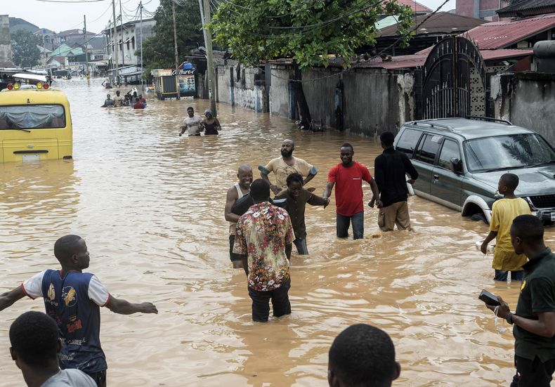 Varias personas caminan por las calles inundadas de Kinsasa, República Democrática del Congo, el domingo 6 de abril de 2025. (AP foto/Samy Ntumba Shambuyi)