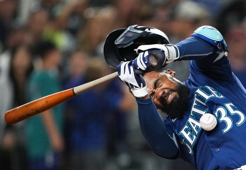El dominicano Teoscar Hernández, de los Marineros de Seattle, recibe un pelotazo durante el juego del miércoles 9 de agosto de 2023, ante los Padres de San Diego (AP Foto/Lindsey Wasson)