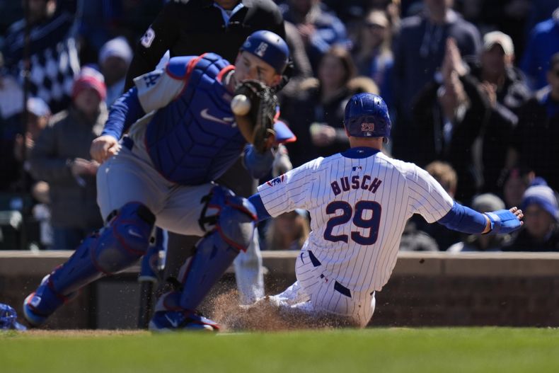 Michael Busch, de los Cachorros de Chicago, se barre para superar la jugada del receptor de los Dodgers de Los Ángeles, Will Smith, para anotar carrera con sencillo de Nick Madrigal durante la segunda entrada del juego de béisbol entre los Cachorros y los Dodgers, el viernes 5 de abril de 2024, en Chicago. (AP Foto/Erin Hooley)
