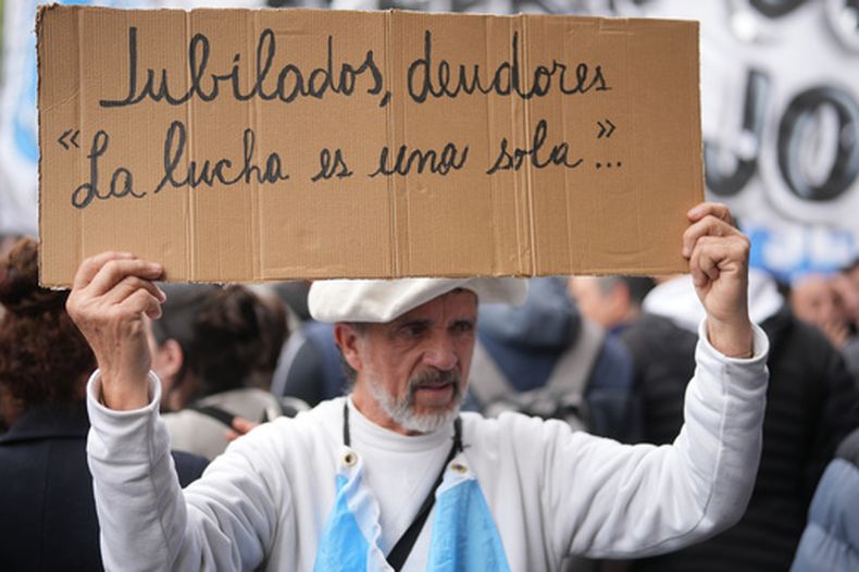 Un manifestante sostiene una pancarta durante una protesta frente al Ministerio de Economía, exigiendo medidas gubernamentales ante la crisis de endeudamiento de los hogares en Buenos Aires, Argentina, el jueves 20 de agosto de 2026. (Foto AP/Víctor R. Caivano)
