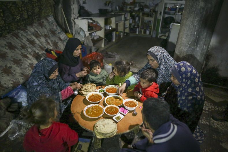 Fatima Al-Absi, a la izquierda, comparte el iftar, la comida que rompe el ayuno, con su hija y sus nietos el primer día de Ramadán en su apartamento dañado en Jabaliya, en el norte de la Franja de Gaza, el sábado 1 de marzo de 2025. (AP Foto/Jehad Alshrafi)
