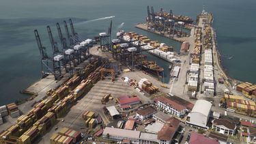 Varios contenedores permanecen apilados mientras las grúas cargan y descargan barcos de carga en el puerto Cristóbal, operado por Panama Ports Company, en Colón, Panamá, el martes 4 de febrero de 2025. (AP Foto/Matias Delacroix)