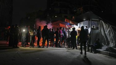Palestinos hacen fila para comprar una cena en un puesto de comida cerca de la playa en un campamento de carpas para desplazados en el puerto de Ciudad de Gaza, el sábado 14 de junio de 2025. (AP Foto/Jehad Alshrafi)