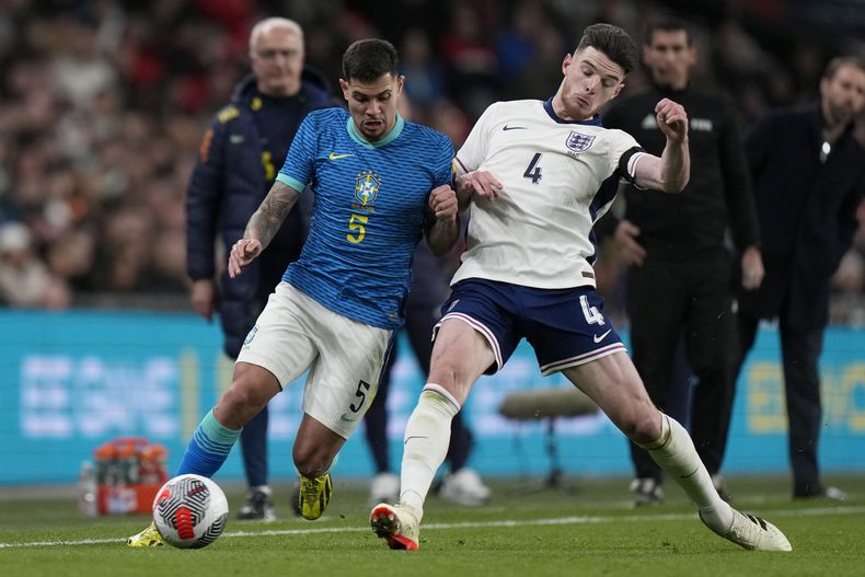 Declan Rice de Inglaterra pelea por el balón con Bruno Guimaraes de Brasil en el encuentro amistoso en el Estadio de Wembley el sábado 23 de marzo del 2024. (AP Foto/Alastair Grant)