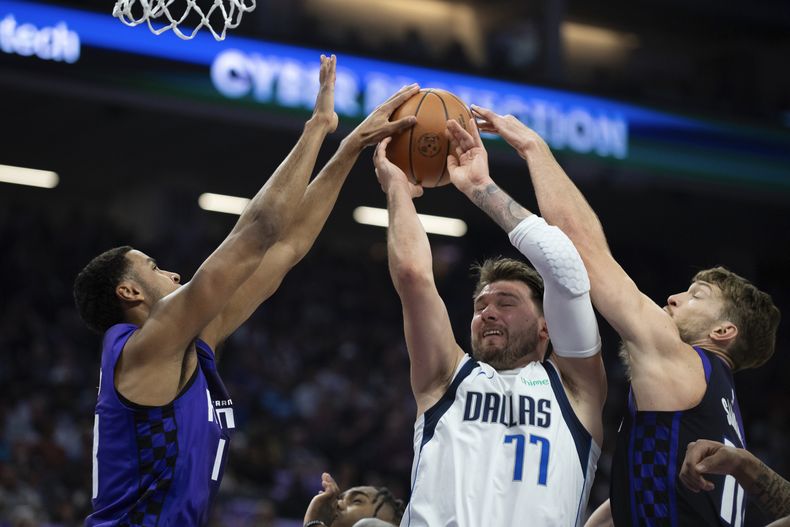 El esloveno Luka Doncic, de los Mavericks de Dallas, intenta disparar entre el lituano Domantas Sabonis (derecha) y Keegan Murray, de los Kings de Sacramento, el martes 26 de marzo de 2024 (AP Foto/José Luis Villegas)