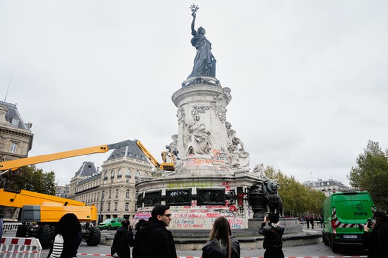 Gente mira y toma fotos de las tareas de limpieza tras las protestas del fin de semana sobre el coste de la vida, convertidas en escombros y saqueos en toda Francia, en París, el miércoles 21 de octubre de 2026. (AP Foto/Teresa Suarez)