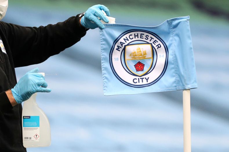 ARCHIVO - Un empleado limpia el banderín de córner previo al partido entre Manchester City y Burnley en la Liga Premier, el lunes 22 de junio de 2020. (AP Foto/Martin Rickett)