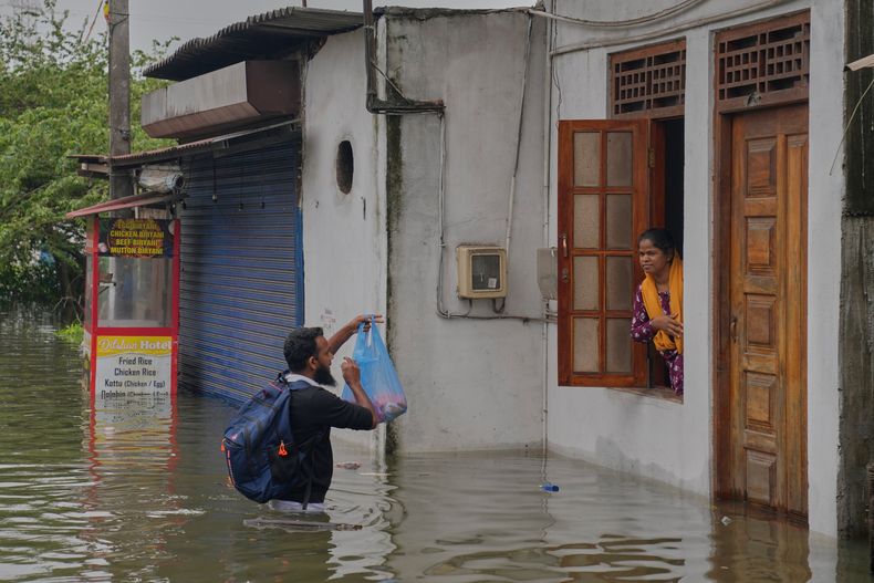 Un hombre brinda ayuda a una mujer atrapada en una casa en una zona inundada de Colombo, Sri Lanka, el sábado 29 de noviembre de 2025. (Foto AP/Eranga Jayawardena)