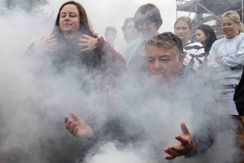 Gente reunida para una ceremonia tradicional aborigen de humo durante la Ceremonia de Reflexión de Duelo We-Akon Dilinja en el Día de Australia, en Melbourne, el domingo 26 de enero de 2025. (Diego Fedele/AAP Image via AP)
