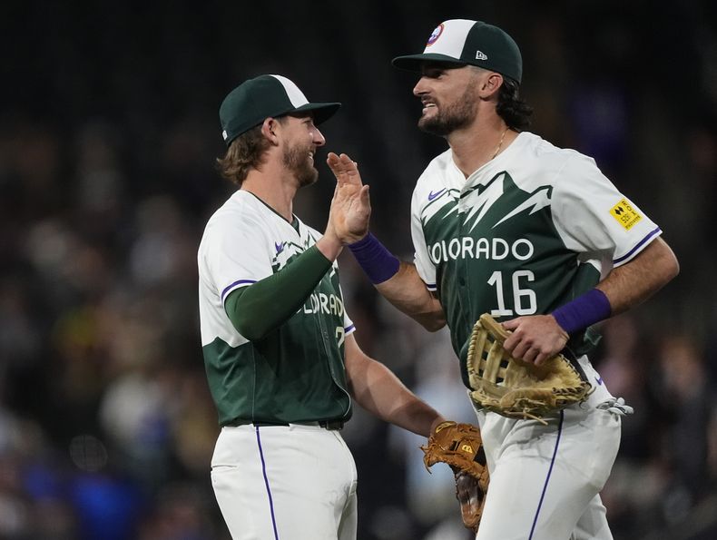 El tercera base de los Rockies de Colorado, Ryan McMahon, a la izquierda, es felicitado por el jardinero central Sam Hilliard después de derrotar a los Reales de Kansas City el sábado 6 de julio de 2024, en Denver. (AP Foto/David Zalubowski)