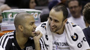 americateve | El argentino Manu Gin&oacute;bili (derecha) r&iacute;e en el banquillo con el franc&eacute;s Tony Parker, durante el partido entre los Spurs de San Antonio y los Pelicans de Nueva Orle&aacute;ns, el lunes 25 de noviembre de 2013 (AP Foto/Eric Gay)